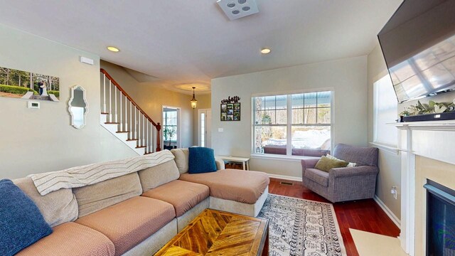 living room featuring baseboards, dark wood-style floors, a fireplace with flush hearth, stairway, and recessed lighting