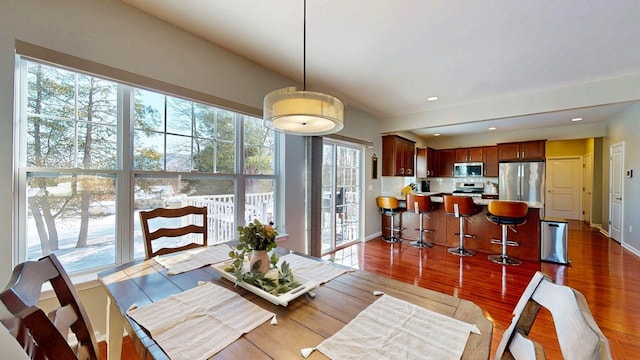 dining space featuring baseboards, wood finished floors, and recessed lighting