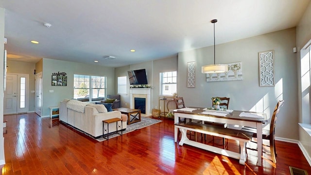 living room with dark wood finished floors, visible vents, and a healthy amount of sunlight