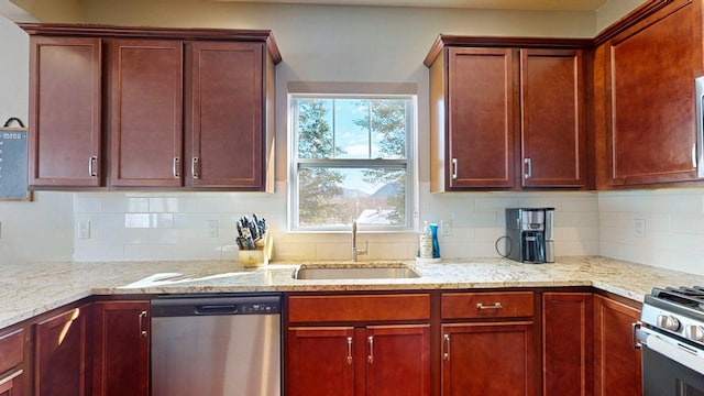 kitchen with reddish brown cabinets, stainless steel appliances, a sink, and light stone countertops