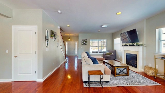 living area featuring dark wood finished floors, recessed lighting, a fireplace with flush hearth, baseboards, and stairs