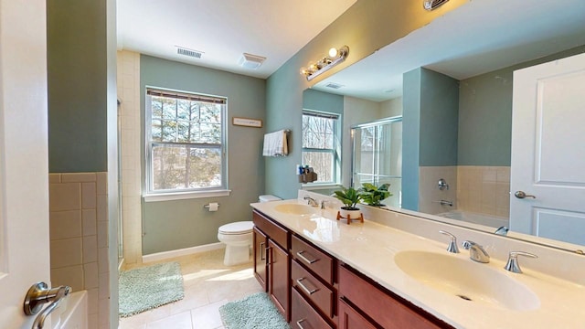 bathroom featuring a garden tub, a sink, toilet, and double vanity