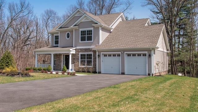 craftsman-style home featuring a garage, aphalt driveway, a front lawn, and covered porch