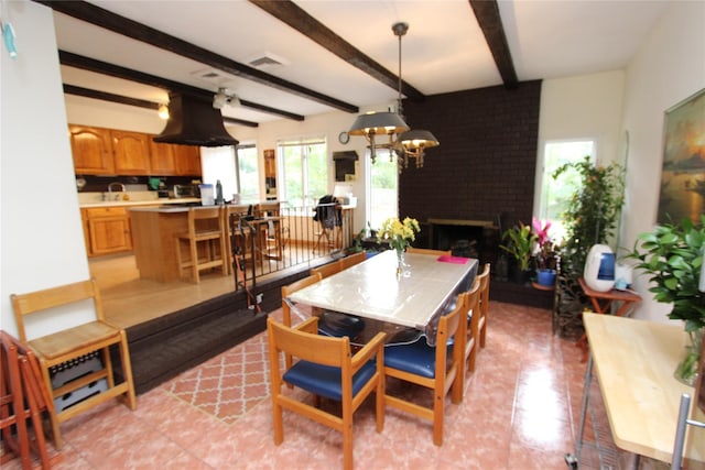 dining space with beamed ceiling, sink, an inviting chandelier, and a fireplace