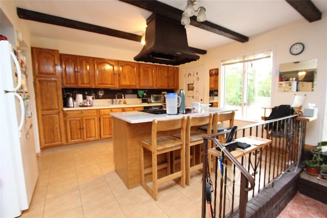 kitchen featuring white refrigerator, island exhaust hood, light tile patterned floors, and beam ceiling