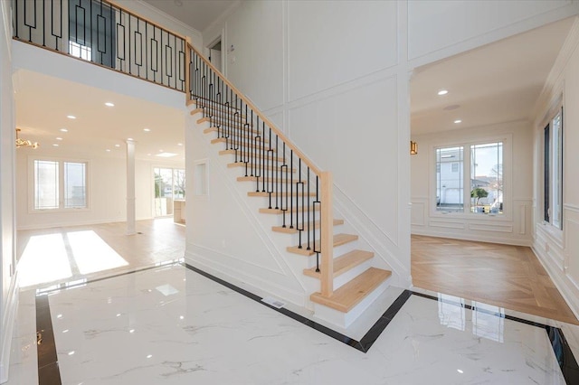 staircase with ornamental molding and ornate columns