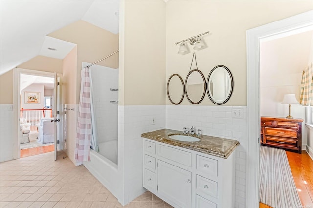 bathroom with tile walls, vanity, vaulted ceiling, tile patterned floors, and shower / bath combo with shower curtain