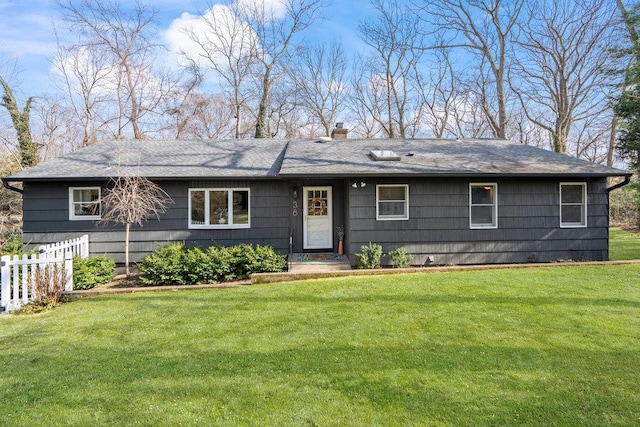 ranch-style house with a shingled roof, a chimney, a front lawn, and fence