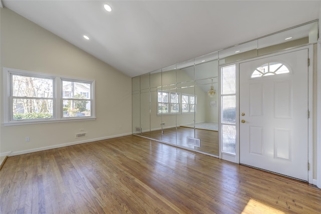 entrance foyer with lofted ceiling, wood finished floors, visible vents, and baseboards