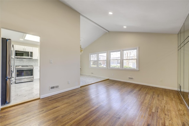 unfurnished living room with lofted ceiling, light wood-style floors, baseboards, and visible vents