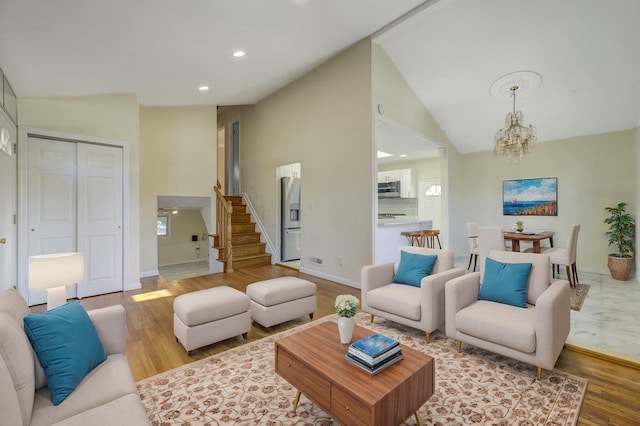 living room featuring light wood-style flooring, stairway, high vaulted ceiling, a notable chandelier, and recessed lighting