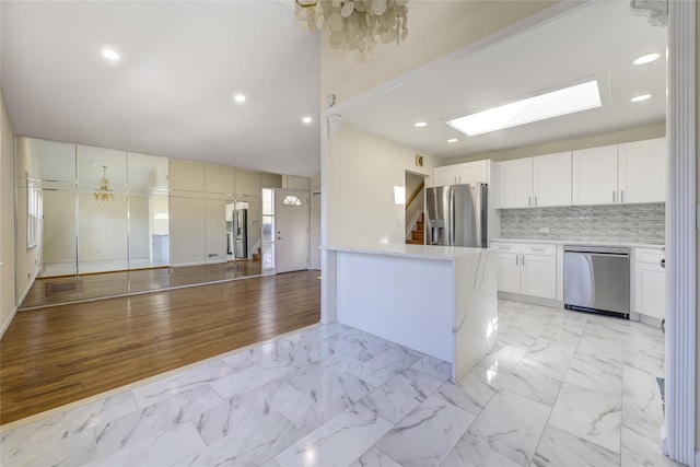 kitchen featuring white cabinets, marble finish floor, stainless steel appliances, and light countertops