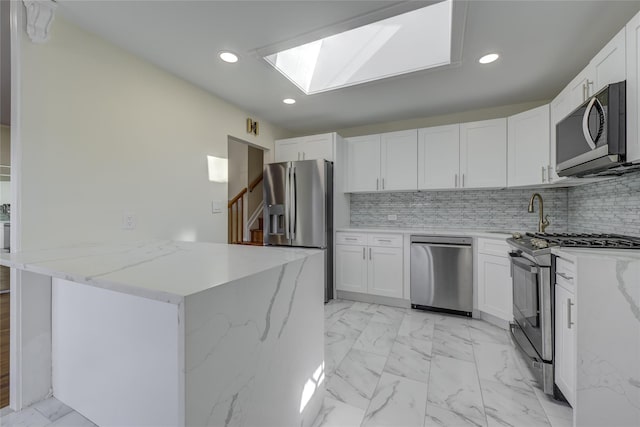 kitchen featuring light stone counters, marble finish floor, appliances with stainless steel finishes, white cabinets, and a sink