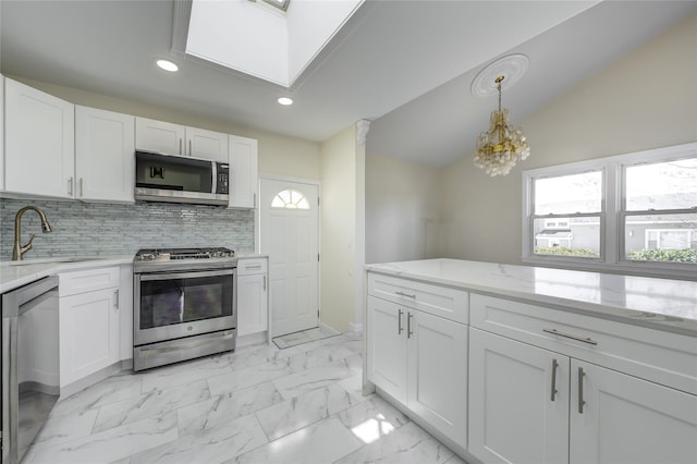 kitchen featuring marble finish floor, hanging light fixtures, appliances with stainless steel finishes, white cabinetry, and a sink