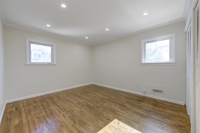 empty room with a healthy amount of sunlight, crown molding, and wood finished floors