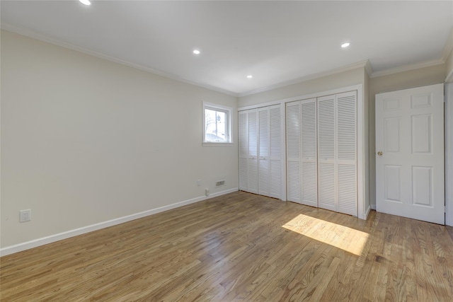 unfurnished bedroom with light wood-type flooring, baseboards, ornamental molding, and two closets