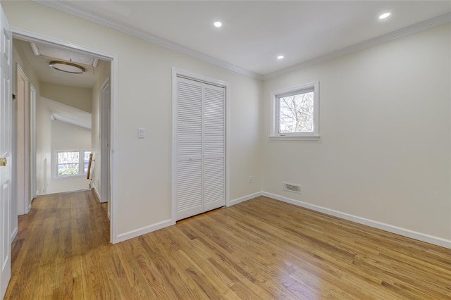 unfurnished bedroom with ornamental molding, light wood-type flooring, visible vents, and multiple windows