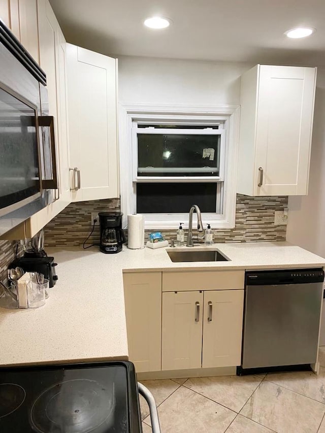 kitchen featuring sink, white cabinets, backsplash, light tile patterned floors, and stainless steel appliances