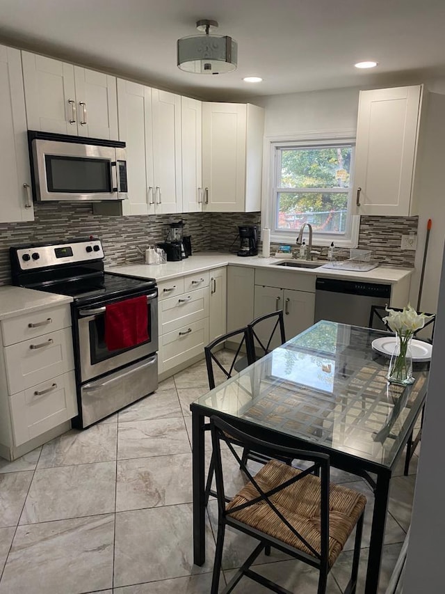 kitchen featuring white cabinetry, stainless steel appliances, sink, and decorative backsplash