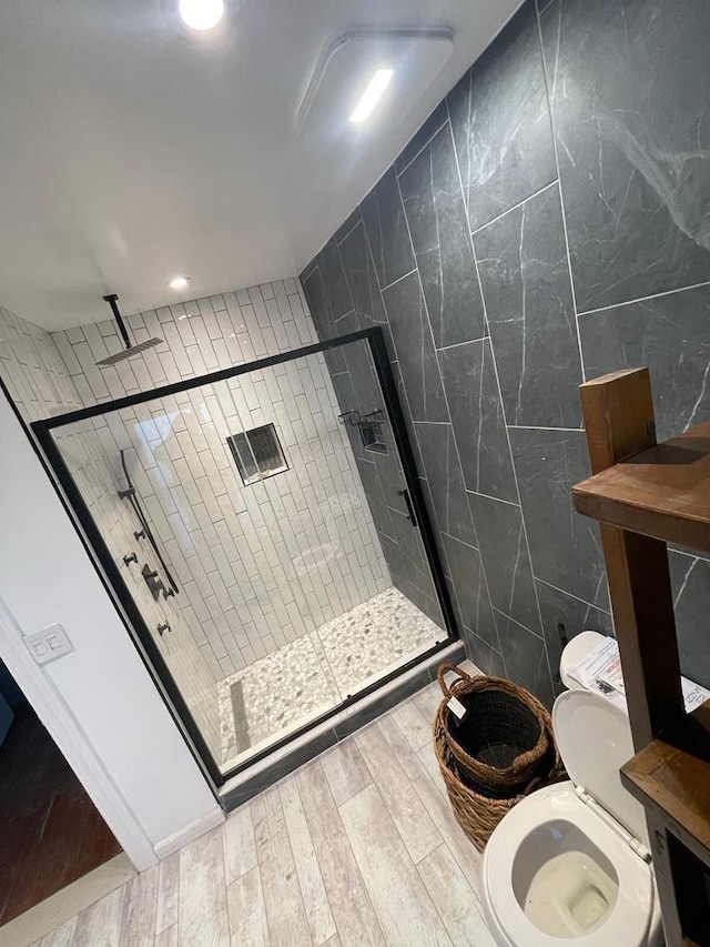 bathroom featuring wood-type flooring, toilet, an enclosed shower, and tile walls