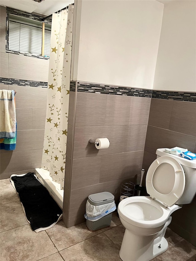 bathroom with a shower, tile walls, tile patterned floors, and toilet