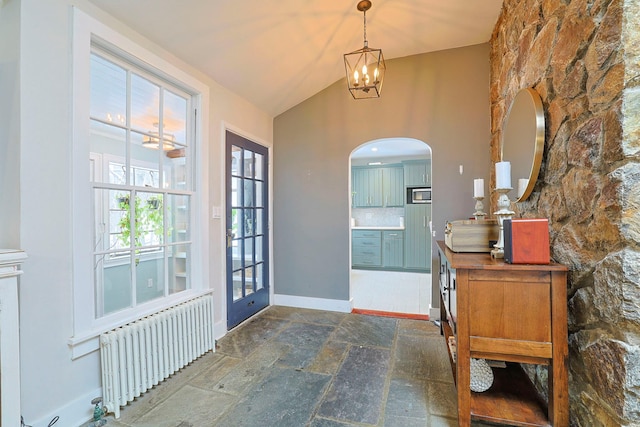 entrance foyer with lofted ceiling, radiator, and a notable chandelier