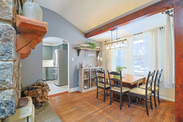 dining space with an inviting chandelier, lofted ceiling with beams, and light hardwood / wood-style floors