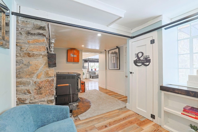 entryway featuring ornamental molding, light hardwood / wood-style floors, and a wood stove