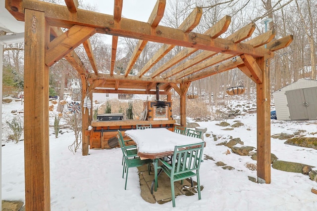 snow covered patio with a storage unit and a hot tub