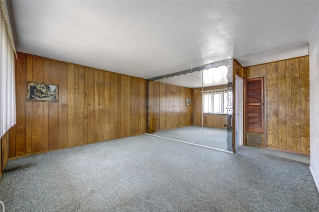 spare room with wood walls and light colored carpet