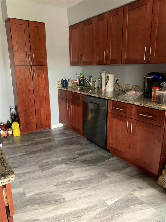 kitchen with stone countertops, dishwasher, and sink