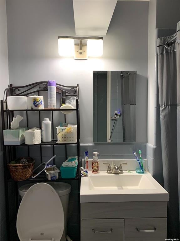 bathroom with walk in shower, vanity, and toilet