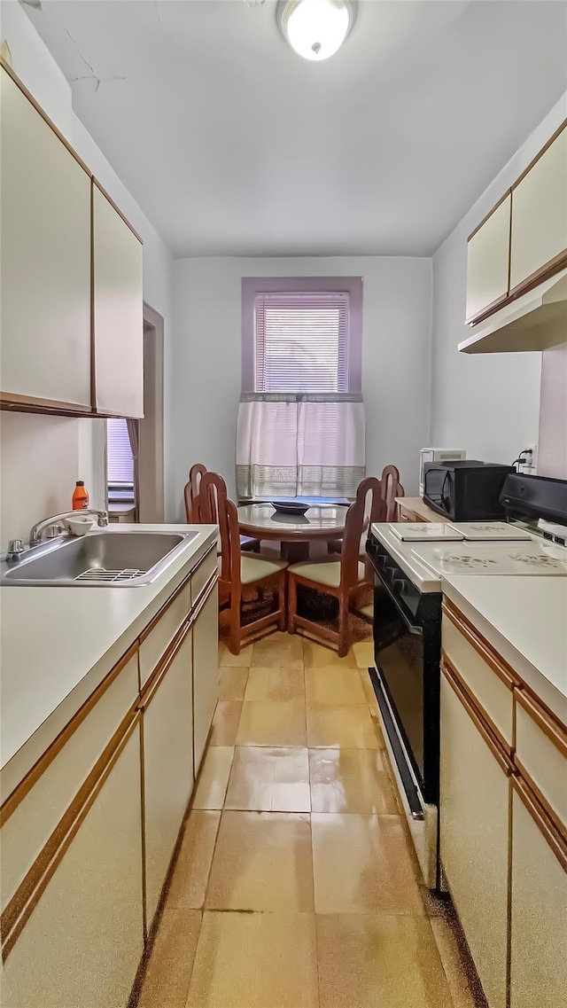 kitchen with sink, light tile patterned floors, black appliances, and white cabinets