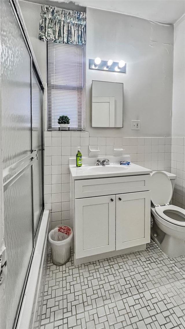 full bathroom with vanity, tile walls, shower / bath combination with glass door, and toilet