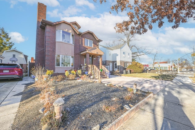 view of front of home featuring a residential view, brick siding, a chimney, and stucco siding