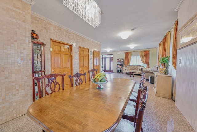 dining area with an inviting chandelier, granite finish floor, and ornamental molding