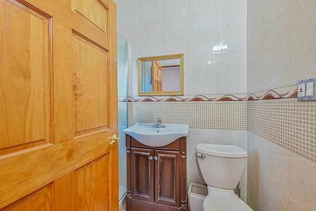 bathroom with tile walls, vanity, and toilet