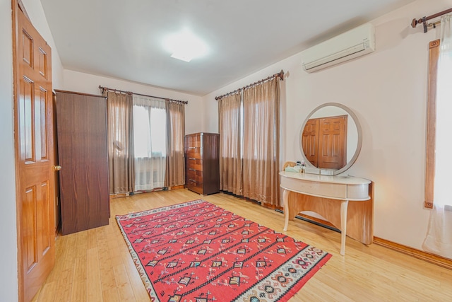 bedroom featuring light wood-style floors and a wall unit AC