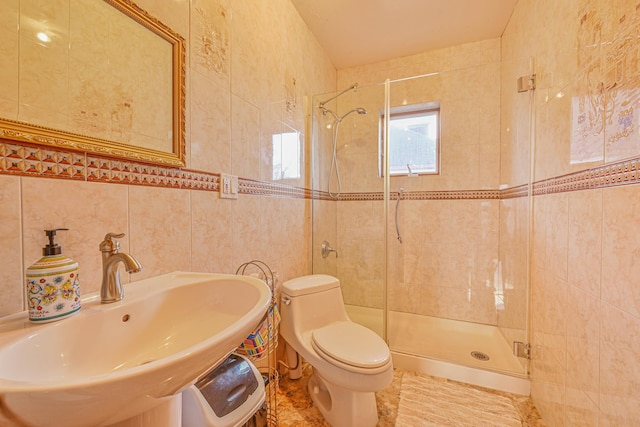 full bath featuring a sink, a shower stall, toilet, and tile walls