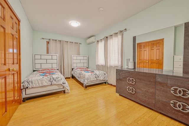 bedroom featuring a wall unit AC and wood finished floors