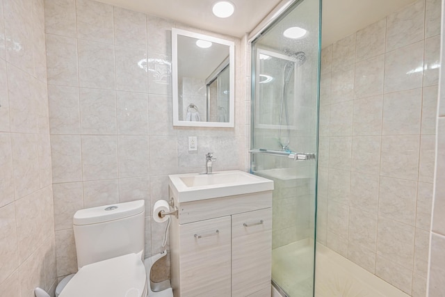 bathroom featuring toilet, tile walls, tiled shower, and vanity