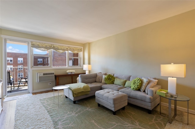 living room featuring a wall unit AC, wood finished floors, and baseboards