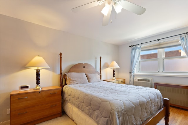 bedroom featuring a ceiling fan, light wood-type flooring, radiator heating unit, and a wall mounted AC