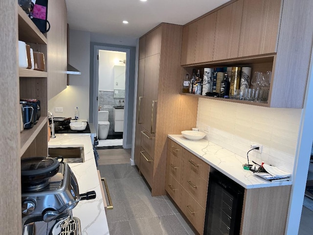 kitchen featuring light stone counters, backsplash, and beverage cooler