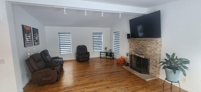 interior space with rail lighting, a fireplace, light wood-type flooring, and lofted ceiling