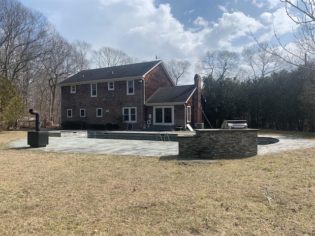 rear view of property with a patio, exterior kitchen, a yard, and a chimney