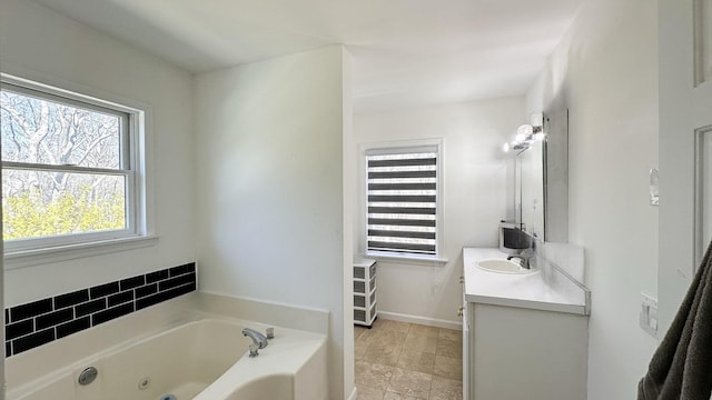 full bath featuring vanity, a whirlpool tub, and baseboards