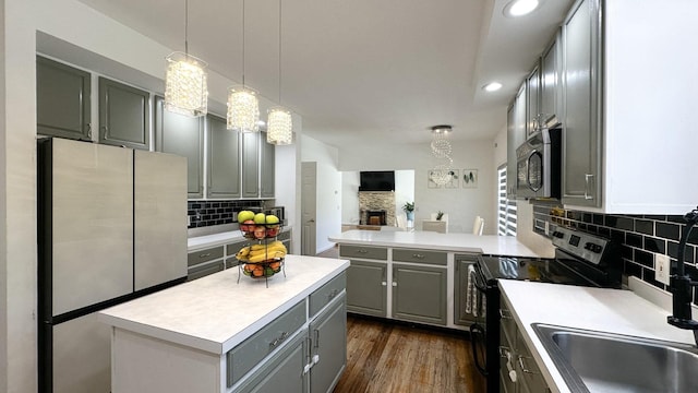 kitchen with light countertops, gray cabinets, stainless steel appliances, decorative backsplash, and a sink