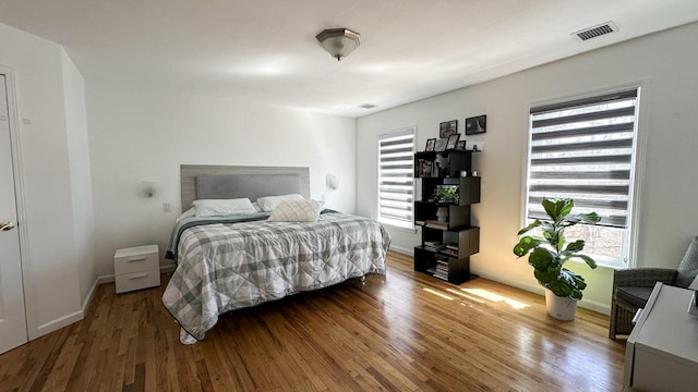 bedroom featuring visible vents, baseboards, and wood finished floors