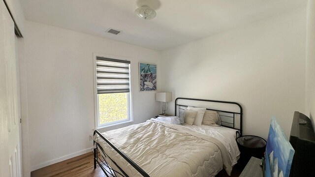 bedroom featuring baseboards, visible vents, and wood finished floors